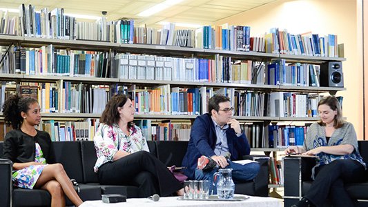 Imagem apresenta debatedoras e mediador da roda de conversa sentados em sofás, com livros ao fundo, na Biblioteca de Manguinhos